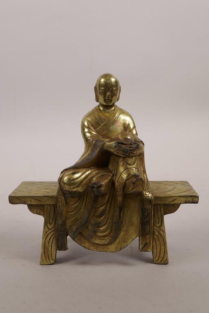 A Chinese gilt bronze figure of Buddha seated on an: A Chinese gilt bronze figure of Buddha seated on an altar bench, 5" wide, 5½" high