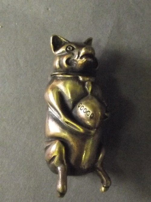 A brass vesta in the form of a pig holding an apple,: A brass vesta in the form of a pig holding an apple, 2'' high