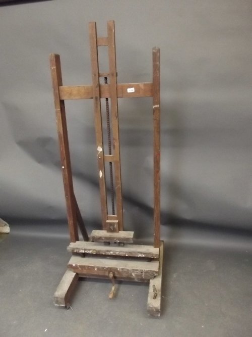 A large C19th oak adjustable artists studio easel with: A large C19th oak adjustable artists studio easel with winding mechanism by John B. Smith, Hampstead, London, 24'' wide, 65½'' high but adjustable