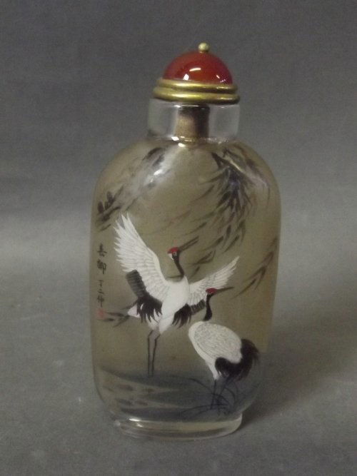 A Chinese reverse painted snuff bottle with decoration: A Chinese reverse painted snuff bottle with decoration of storks under bamboo, signed with inscription, 3¾'' high