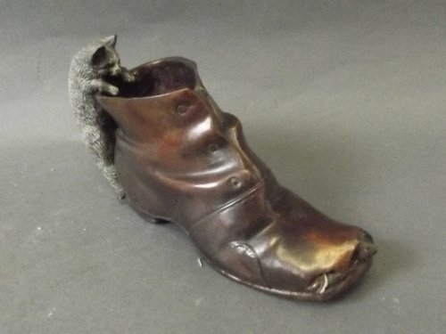 A cold painted bronze cat climbing a boot, impressed: A cold painted bronze cat climbing a boot, impressed stamp 'Geschutzt', 5¾'' long