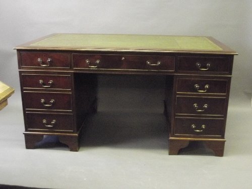 A Georgian style mahogany 9 drawer pedestal desk with: A Georgian style mahogany 9 drawer pedestal desk with an inset leather top, 60'' x 35½'', 31½'' high