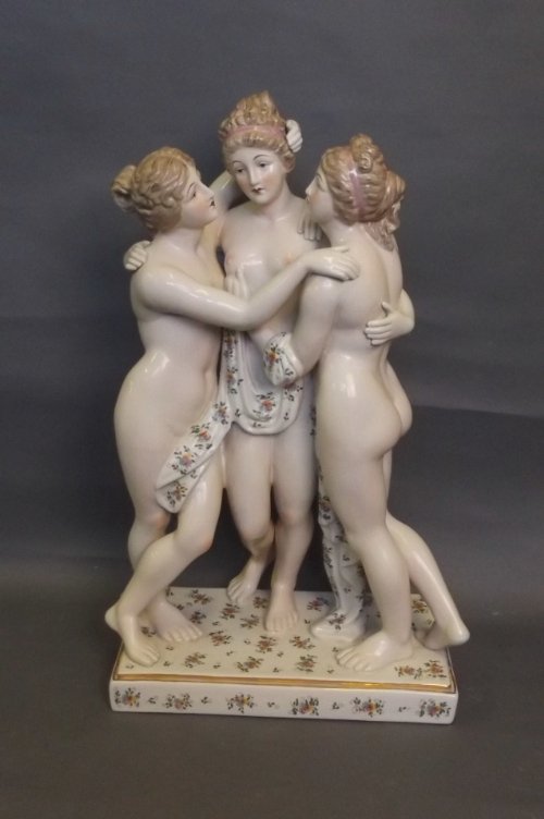 A large pottery group of the Three Graces standing on: A large pottery group of the Three Graces standing on floral decorated base outlined in gilt, 19½'' high