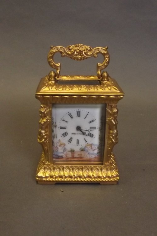 An ornate brass carriage clock with painted decoration : An ornate brass carriage clock with painted decoration of 2 winged cherubs to the clock face, 2'' x 2¾'', 3½'' high