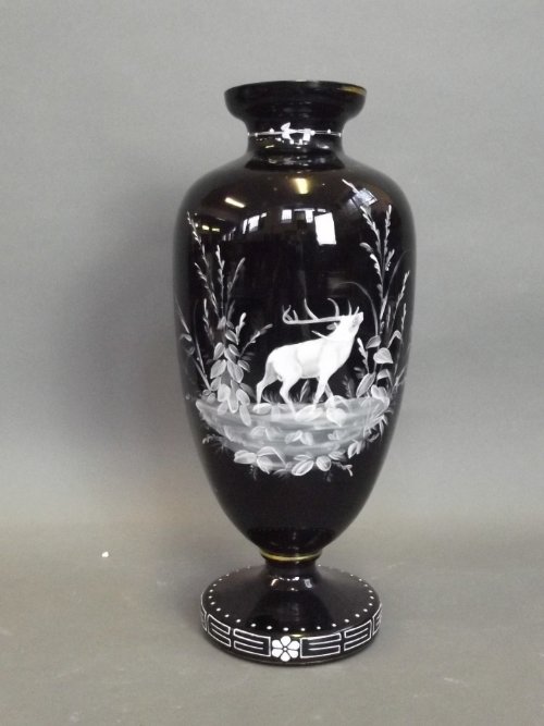 A black glass vase with enamel decoration to sides of a: A black glass vase with enamel decoration to sides of a stag, the base decorated with flowers and enamelled geometric patterns, with gilt rim, 13'' high