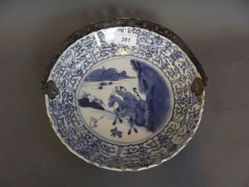 An early C18th Chinese blue and white pottery shallow: An early C18th Chinese blue and white pottery shallow bowl with a silver plated handle, painted with hunters on horseback, 6 character mark, 9'' diameter (AF)