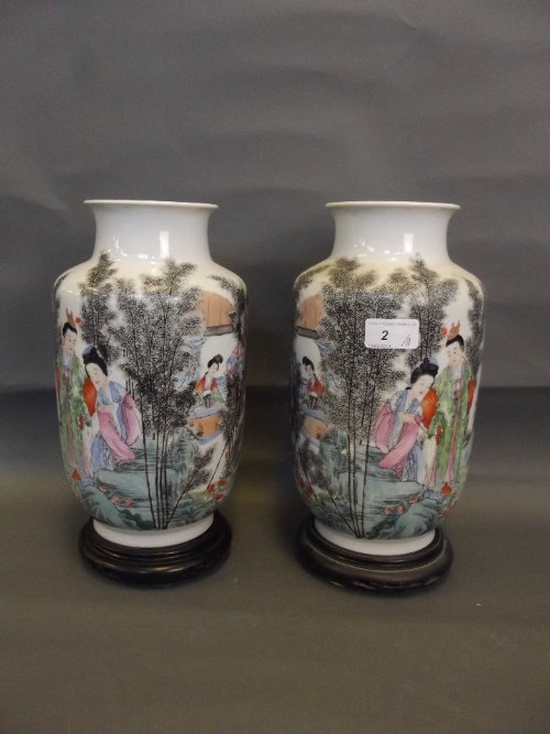 A pair of Chinese Republic period pottery vases painted: A pair of Chinese Republic period pottery vases painted in coloured enamels with figures in a garden setting, on hardwood stands, 12½'' high