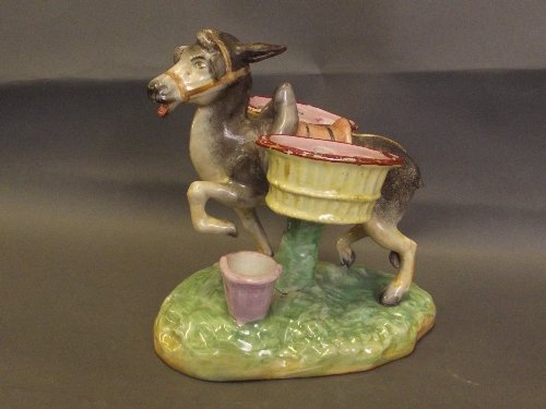 A Thomas Parr Staffordshire figure of a donkey carrying: A Thomas Parr Staffordshire figure of a donkey carrying two baskets, on a green and yellow base, circa 1870, 7'' high (tail missing)