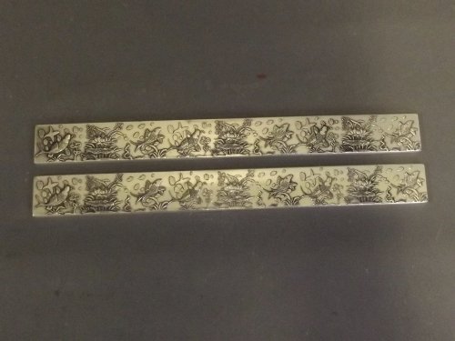 A pair of Chinese white metal scroll weights with: A pair of Chinese white metal scroll weights with relief decoration of a carp and water lilies, impressed mark to back