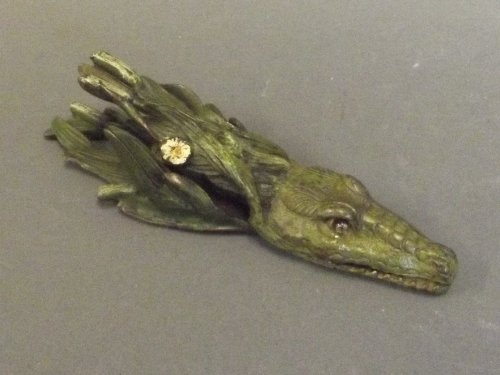 A cold painted bronze paper clip in the form of a: A cold painted bronze paper clip in the form of a crocodile swimming in reeds, 5½'' long