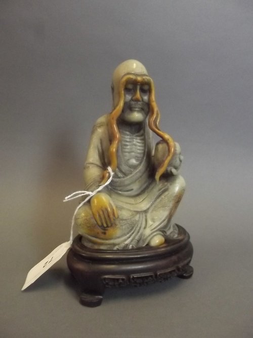 A Chinese caved soapstone figure of a seated Lohan, on: A Chinese caved soapstone figure of a seated Lohan, on a carved wood stand, 7'' high