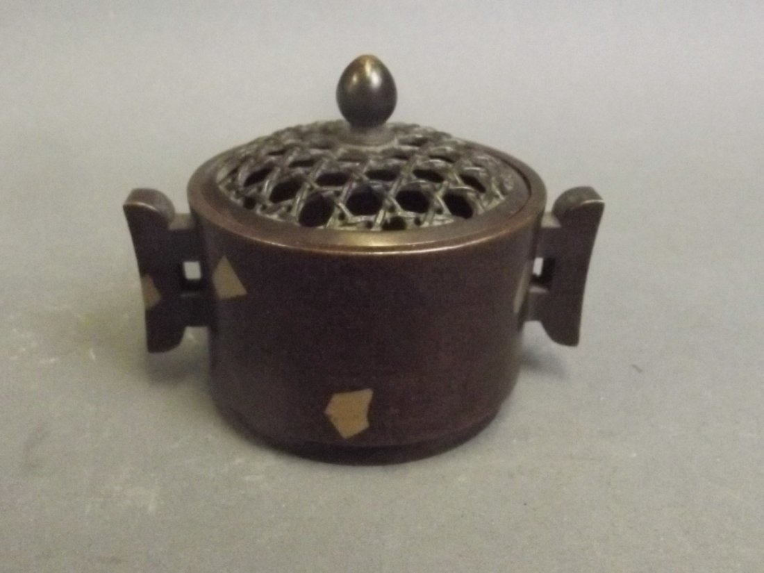 A Chinese twin handled circular bronze censer with: A Chinese twin handled circular bronze censer with inset gilt decoration and reticulated lid, impressed mark, 2½'' diameter