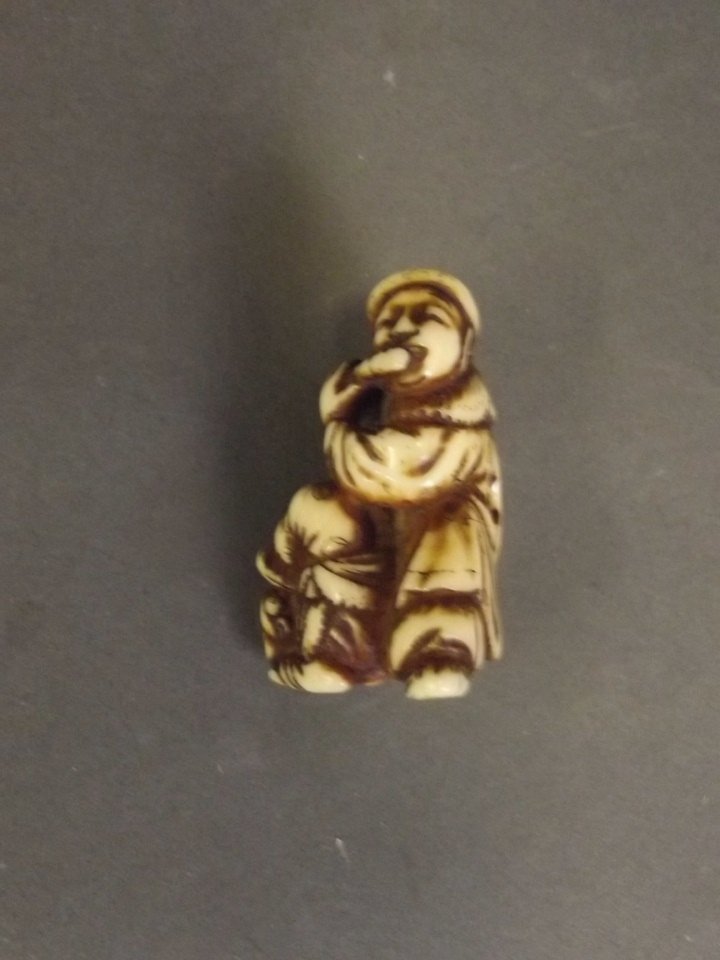 A C19th Japanese carved ivory netsuke in the form of a: A C19th Japanese carved ivory netsuke in the form of a gentleman playing a flute and an acrobatic boy, signed, 1½'' high