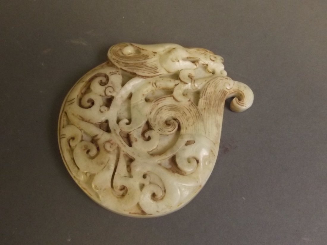 A Chinese mottled celadon jade pendant with carved: A Chinese mottled celadon jade pendant with carved dragon decoration, 3'' long