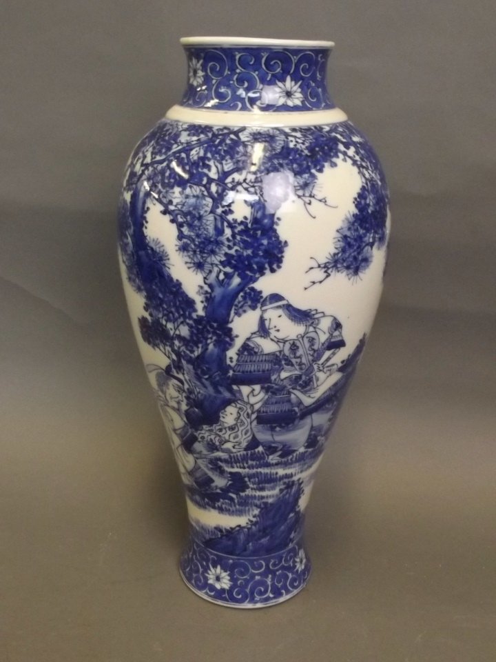 An Oriental blue and white vase decorated with figures: An Oriental blue and white vase decorated with figures under a tree, 12½'' high