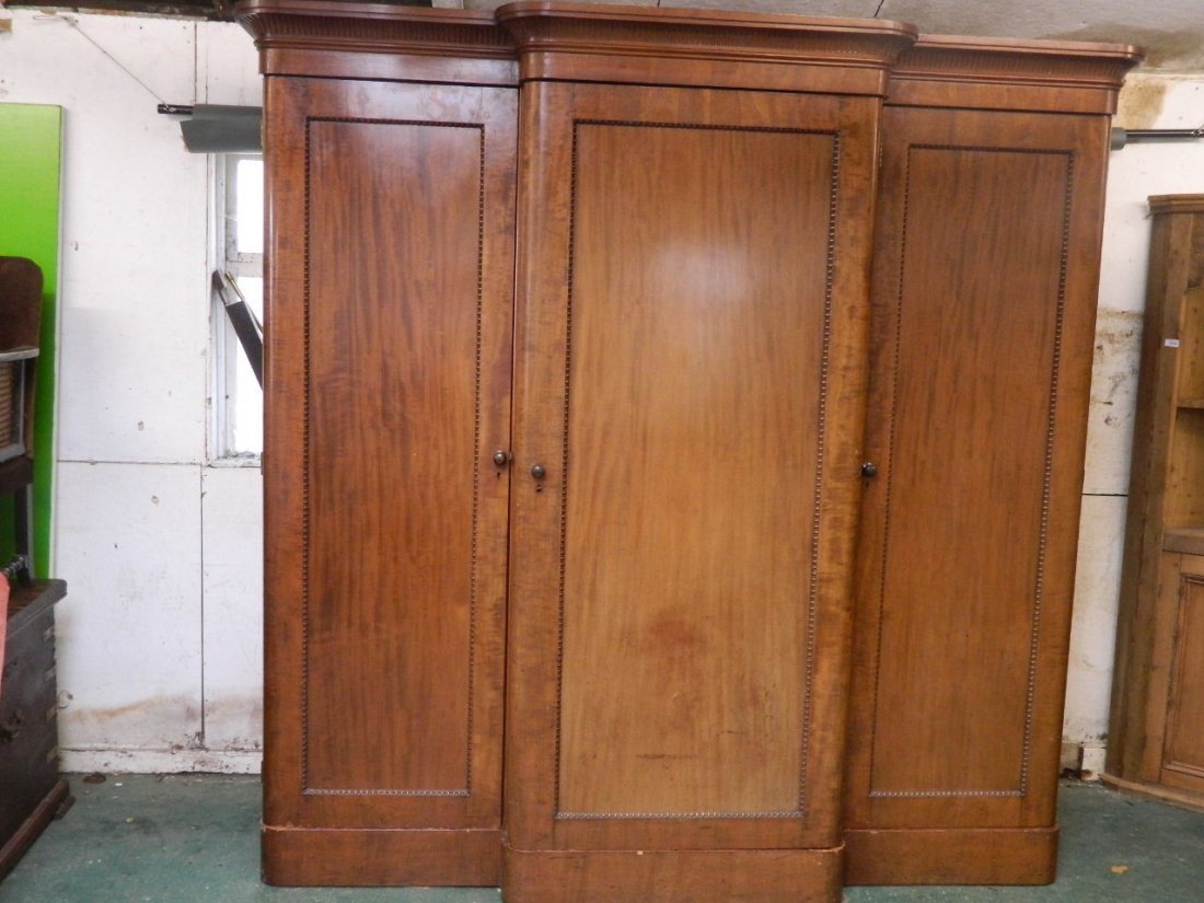 A good early Victorian mahogany breakfront triple: A good early Victorian mahogany breakfront triple wardrobe, the centre section fitted with slides, drawers and interior full length mirror, 85'' x 27'', 84'' high