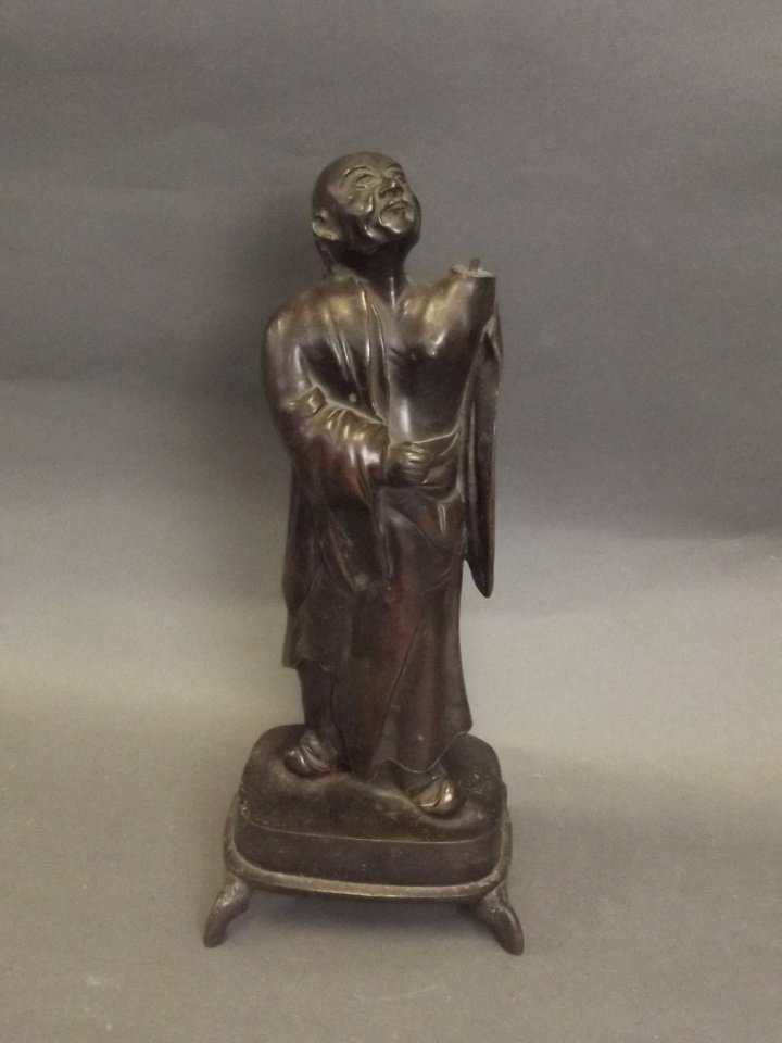 An Oriental bronze figure of a robed gentleman,: An Oriental bronze figure of a robed gentleman, standing on a raised footed base, 12'' high (AF)