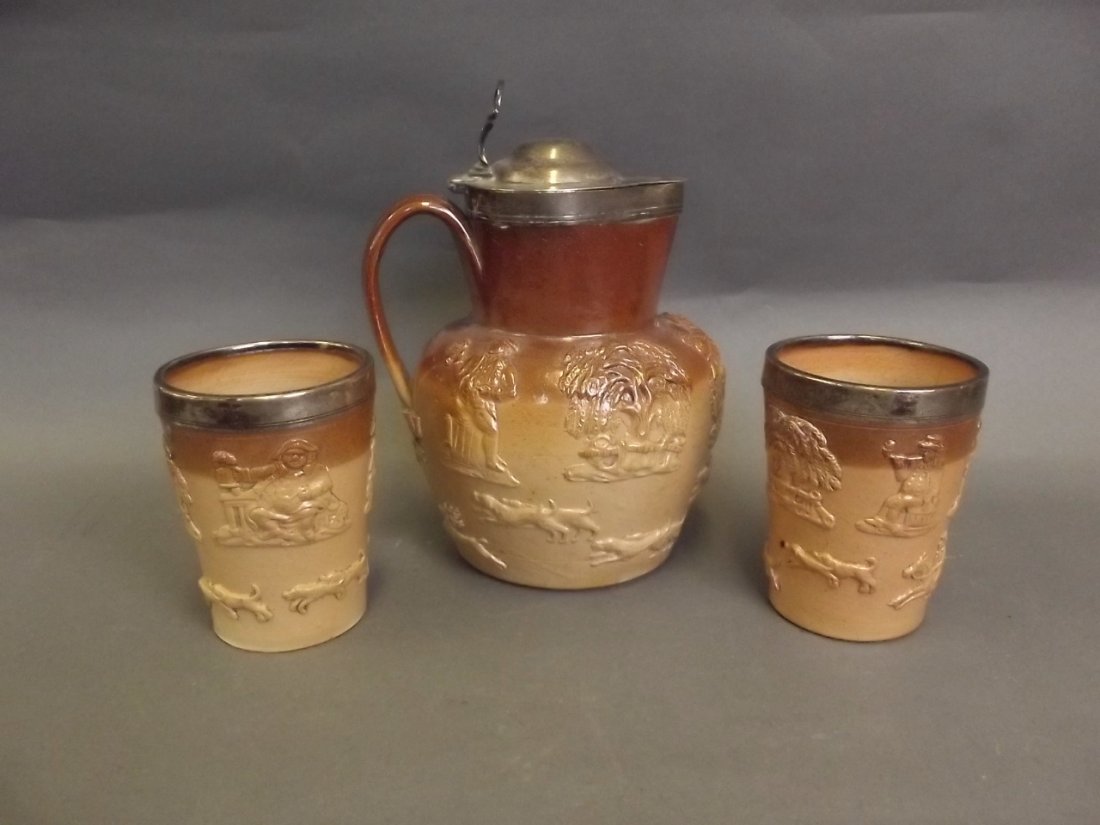A C19th Stoneware hunting jug and matching beakers, all: A C19th Stoneware hunting jug and matching beakers, all with Hallmarked silver mounts, London 1875, maker E.C.B., jug 8½'' high (AF with faults)