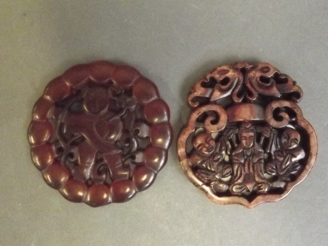 Two Chinese pierced and carved circular stone pendants,: Two Chinese pierced and carved circular stone pendants, one decorated with a figure holding a ruyi, the other depicting a Votive figure and two attendants, 2¼'' diameter