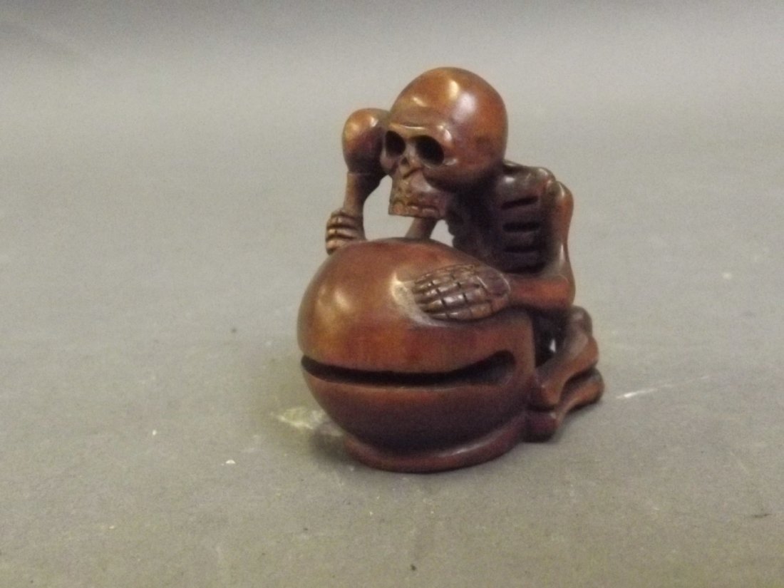 A small signed Netsuke in the form of a skeleton: A small signed Netsuke in the form of a skeleton banging a drum, 2'' high