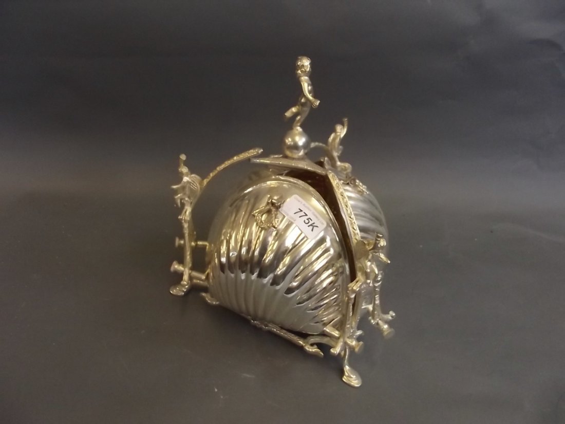 A silver plated biscuitier with three fold out clam: A silver plated biscuitier with three fold out clam shells decorated with winged cherubs, 10'' high