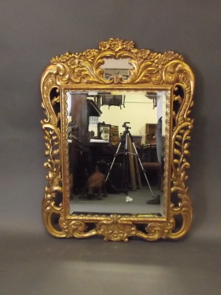 A C19th carved giltwood Continental wall mirror: A C19th carved giltwood Continental wall mirror decorated with flowers, 42½'' x 32''