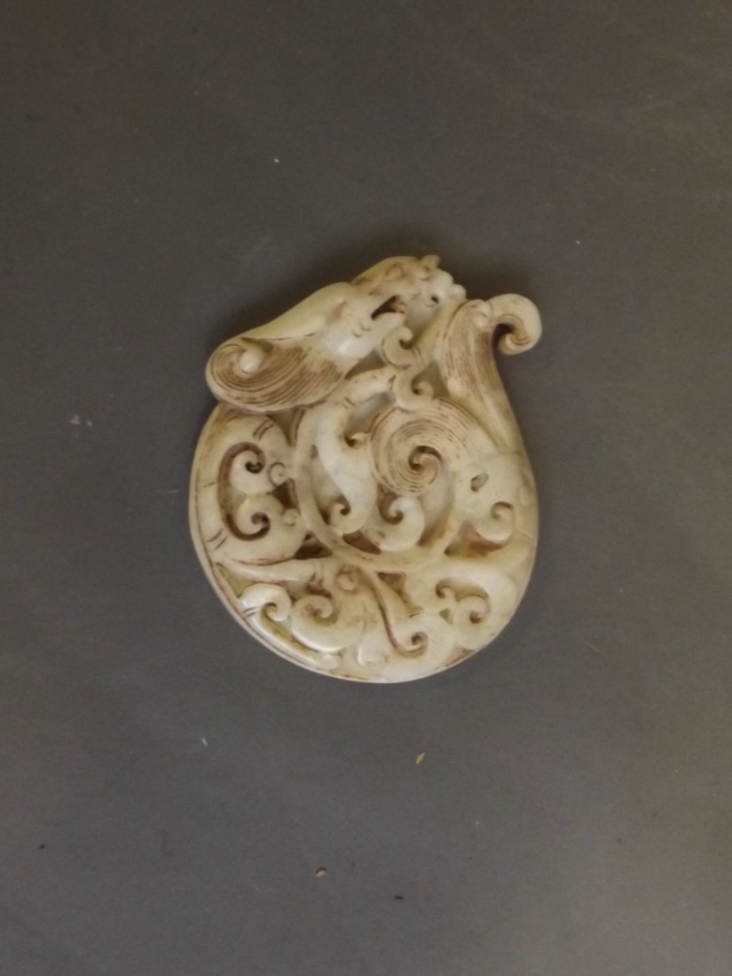 A Chinese mottled celadon jade pendant with carved: A Chinese mottled celadon jade pendant with carved dragon decoration, 3'' long