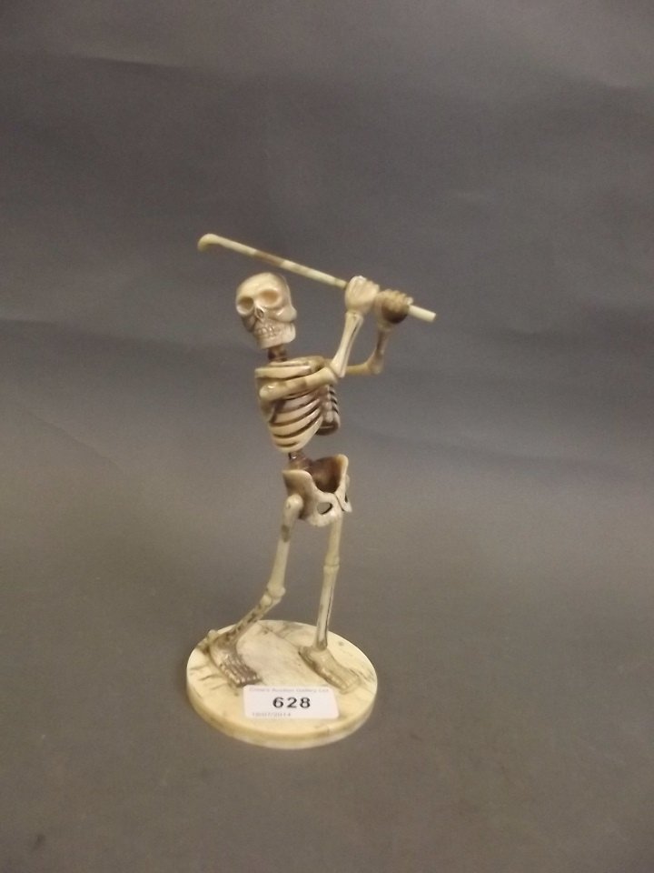 A carved sectional bone model of a skeleton playing: A carved sectional bone model of a skeleton playing golf, 7¼'' high