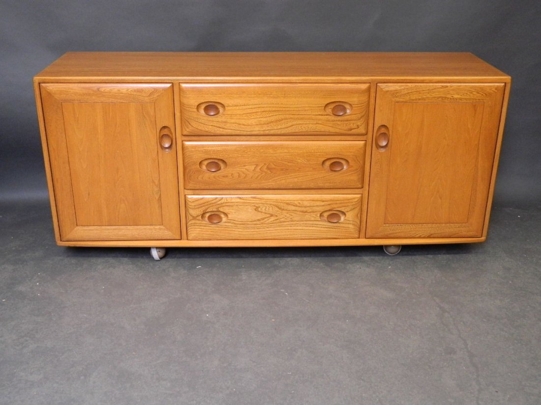 An Ercol oak sideboard with three central drawers: An Ercol oak sideboard with three central drawers flanked by cupboards, 60'' wide