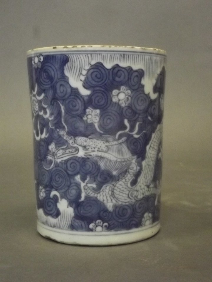 A Chinese porcelain brushpot with blue and white: A Chinese porcelain brushpot with blue and white decoration of a dragon amongst the clouds, 6'' high