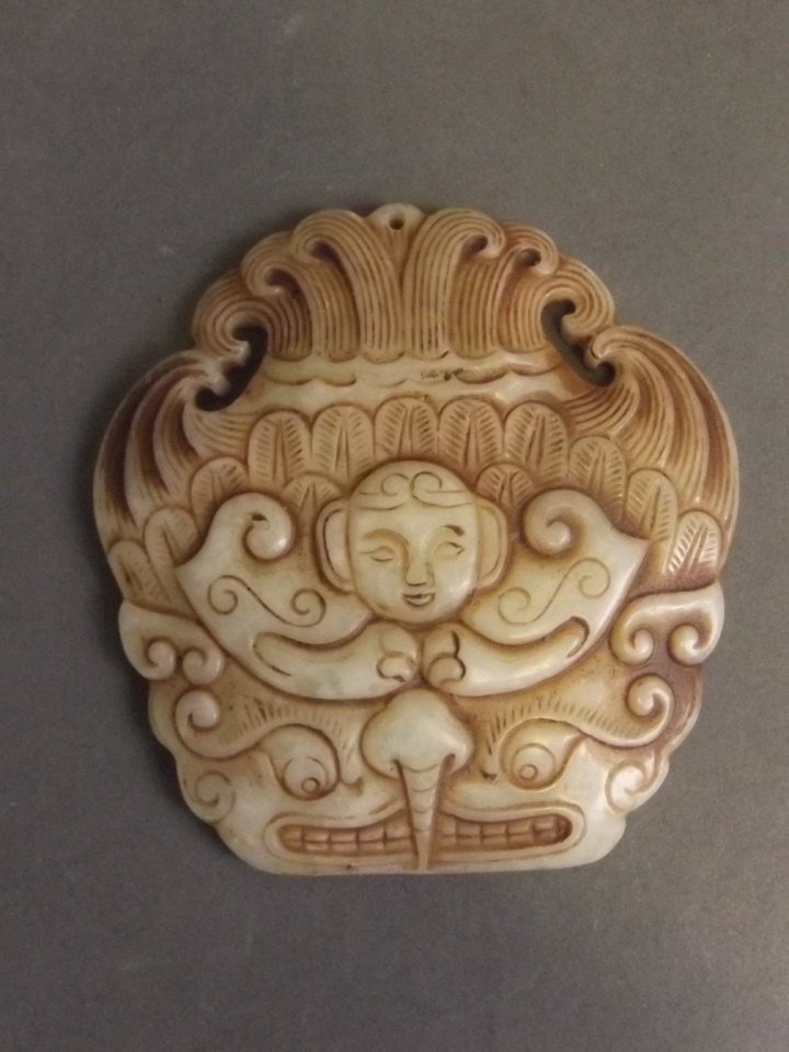 A Chinese cream jade pendant with a woman's face and: A Chinese cream jade pendant with a woman's face and mythical creature, 2¾'' long