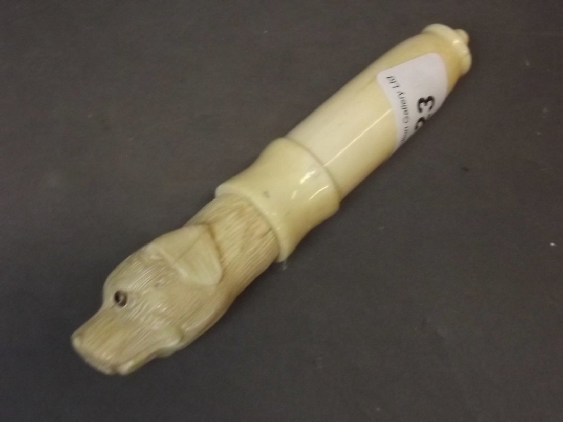 A bone corkscrew carved with a dog's head, with inset: A bone corkscrew carved with a dog's head, with inset glass eyes, 5½'' long