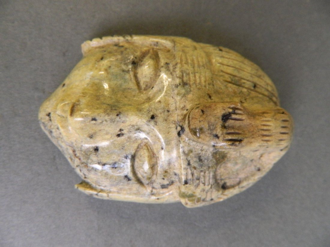 A large stone carved pendant in the form of a serpent: A large stone carved pendant in the form of a serpent and a mask head, possibly South American, 3'' long