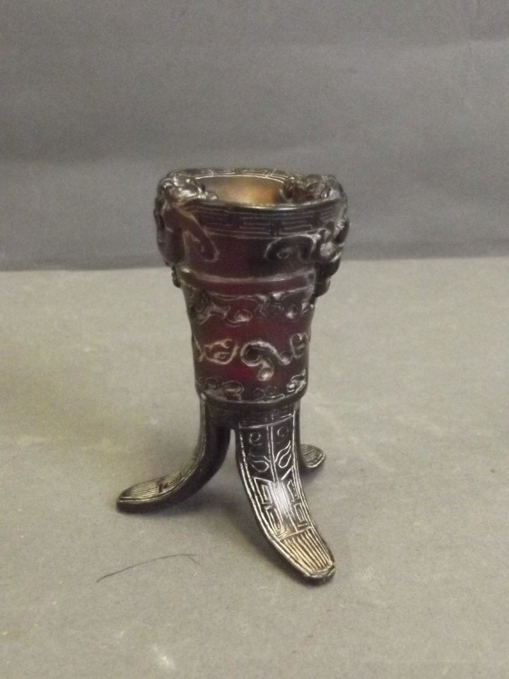 A Chinese miniature horn libation cup with carved: A Chinese miniature horn libation cup with carved tripod supports and climbing kylin decoration, 3'' high