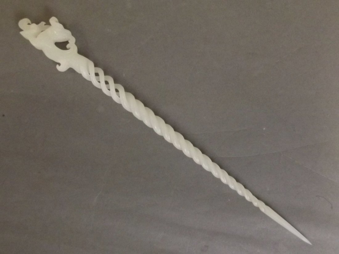 A Chinese white jade carved and pierced hairpin with: A Chinese white jade carved and pierced hairpin with spiral and dragon decoration, 9½'' long