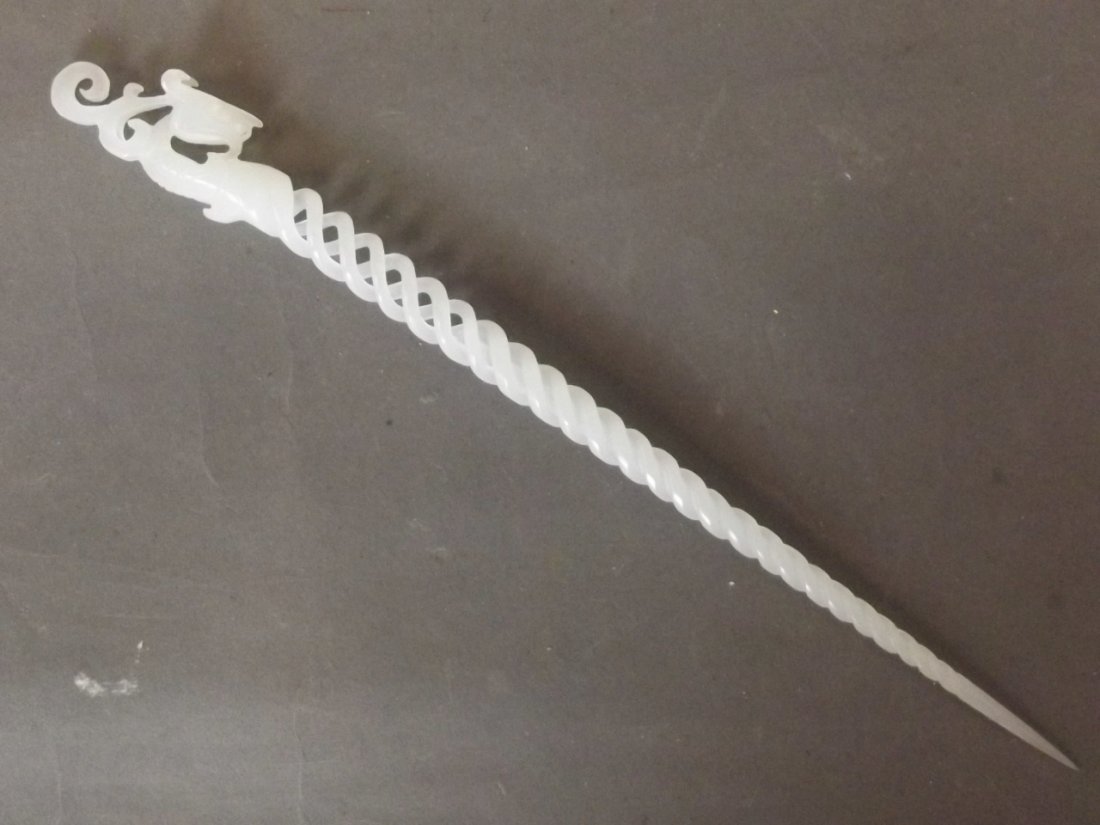 A Chinese white jade pierced hairpin with spiral: A Chinese white jade pierced hairpin with spiral decoration and a carved dragon head handle, 9¼'' long