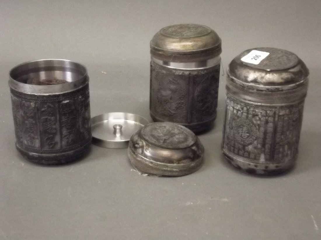A set of three Chinese white metal tea caddies, one: A set of three Chinese white metal tea caddies, one with designs of a phoenix and dragons, the others with Chinese calligraphy, all with tea cakes, 5½'' high