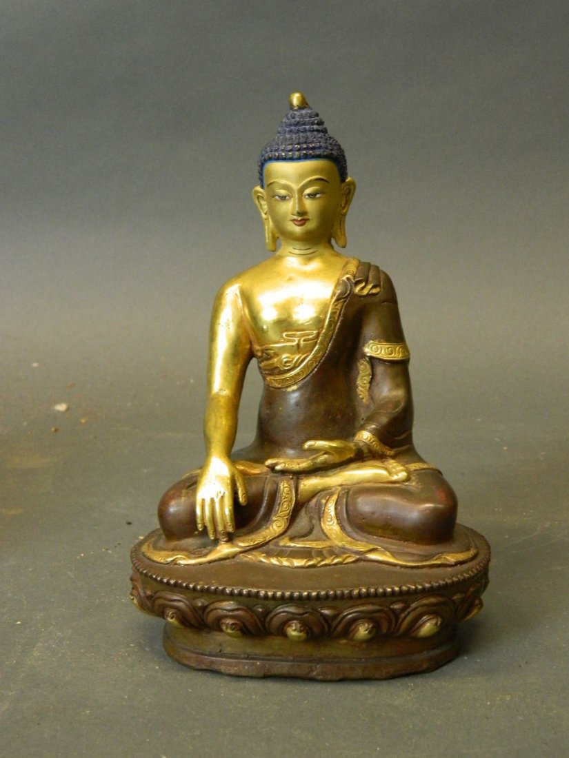 An Eastern gilt bronze and cold painted figure of: An Eastern gilt bronze and cold painted figure of Buddha seated upon a stylised lotus throne, 8'' high