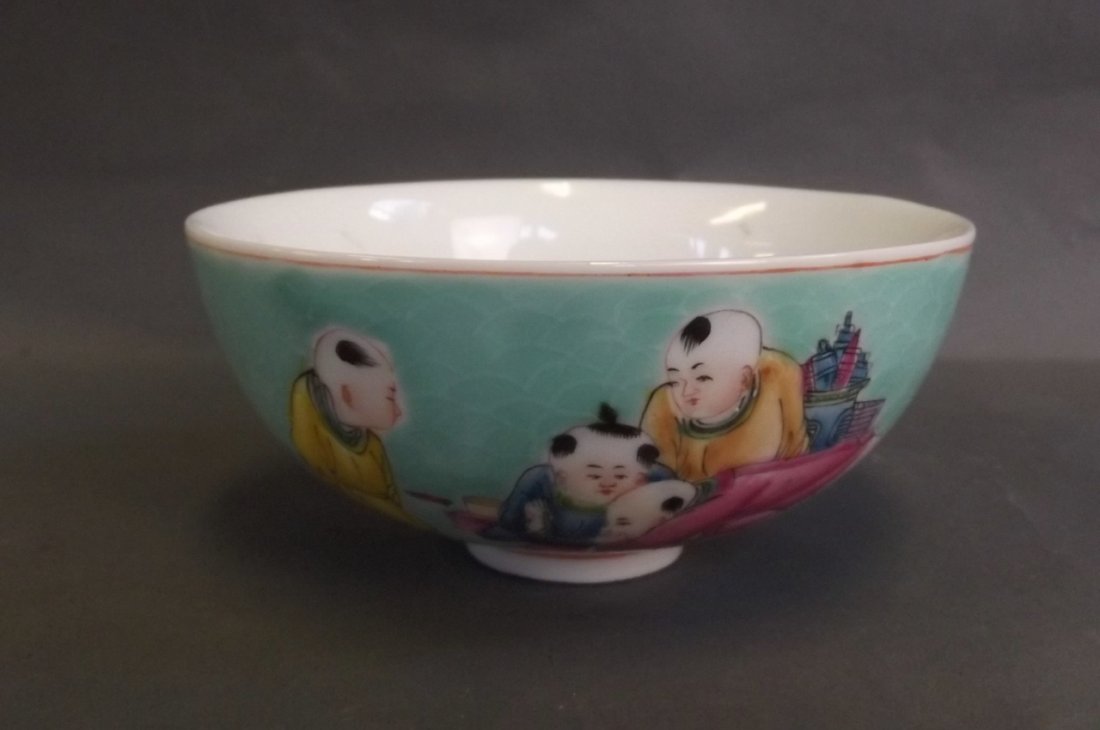 A Chinese green ground porcelain rice bowl with painted: A Chinese green ground porcelain rice bowl with painted enamel decoration of a peach to centre and boys playing with spinning tops to exterior, 4 character mark to base, 4¼'' diameter
