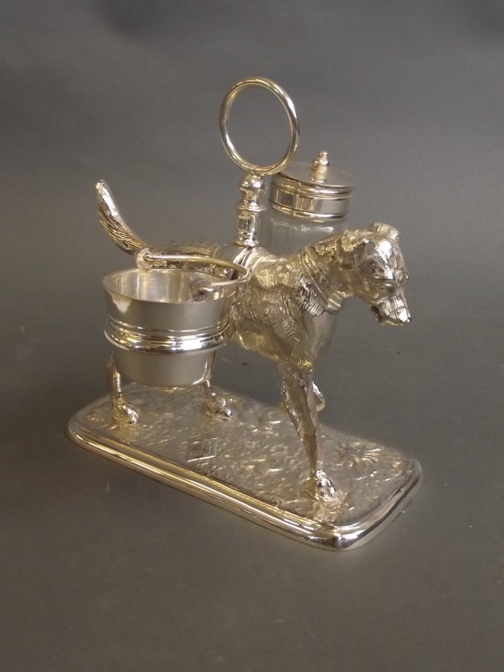 A silver plated condiment set in the form of a dog: A silver plated condiment set in the form of a dog carrying two baskets, 5½'' high