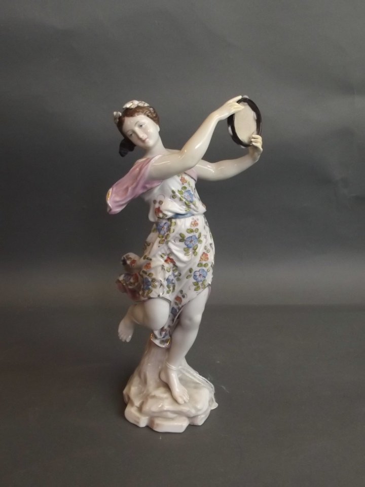 A Continental porcelain figure of a dancing girl with: A Continental porcelain figure of a dancing girl with tambourine, crossed swords mark to base, 8'' high