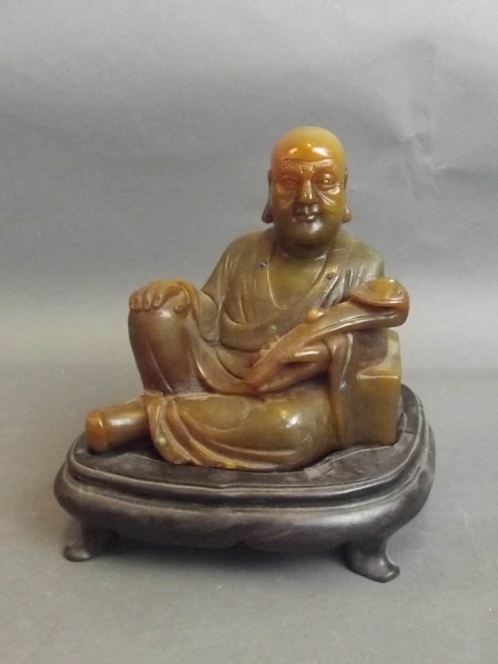 A Chinese carved figure of Buddha holding a ruyi on a: A Chinese carved figure of Buddha holding a ruyi on a hardwood stand, 5½'' high