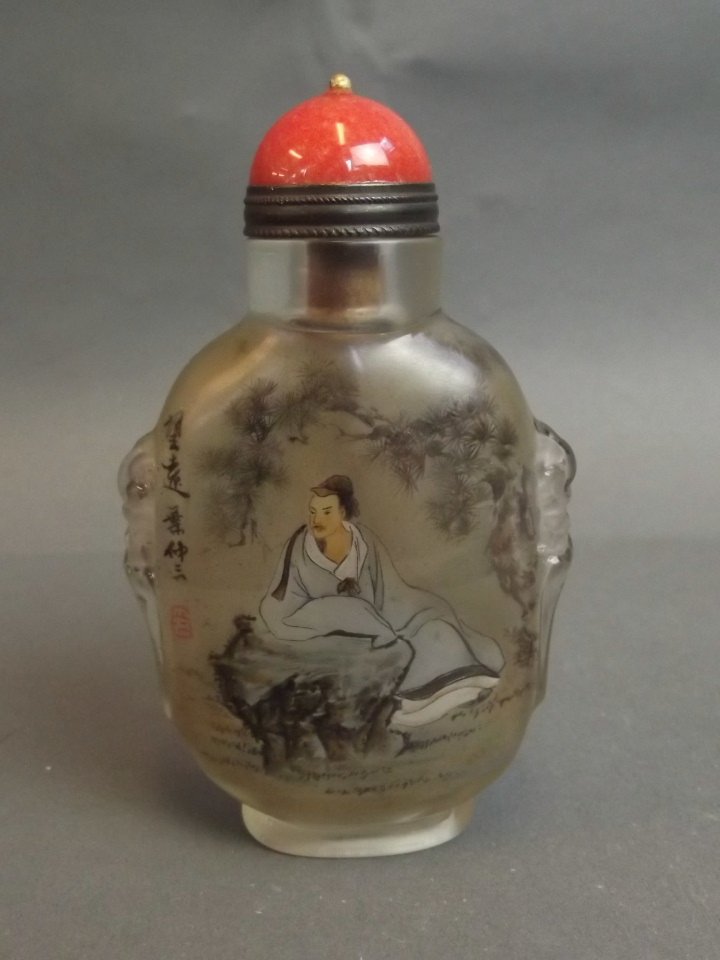 A Chinese twin handled glass snuff bottle with reverse: A Chinese twin handled glass snuff bottle with reverse painted decoration of a blue robed gentleman in a landscape setting, 3¼'' high