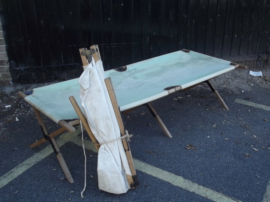 A white canvas camp bed and another in faded green,: A white canvas camp bed and another in faded green, c1940, 75'' x 32'', 18'' high