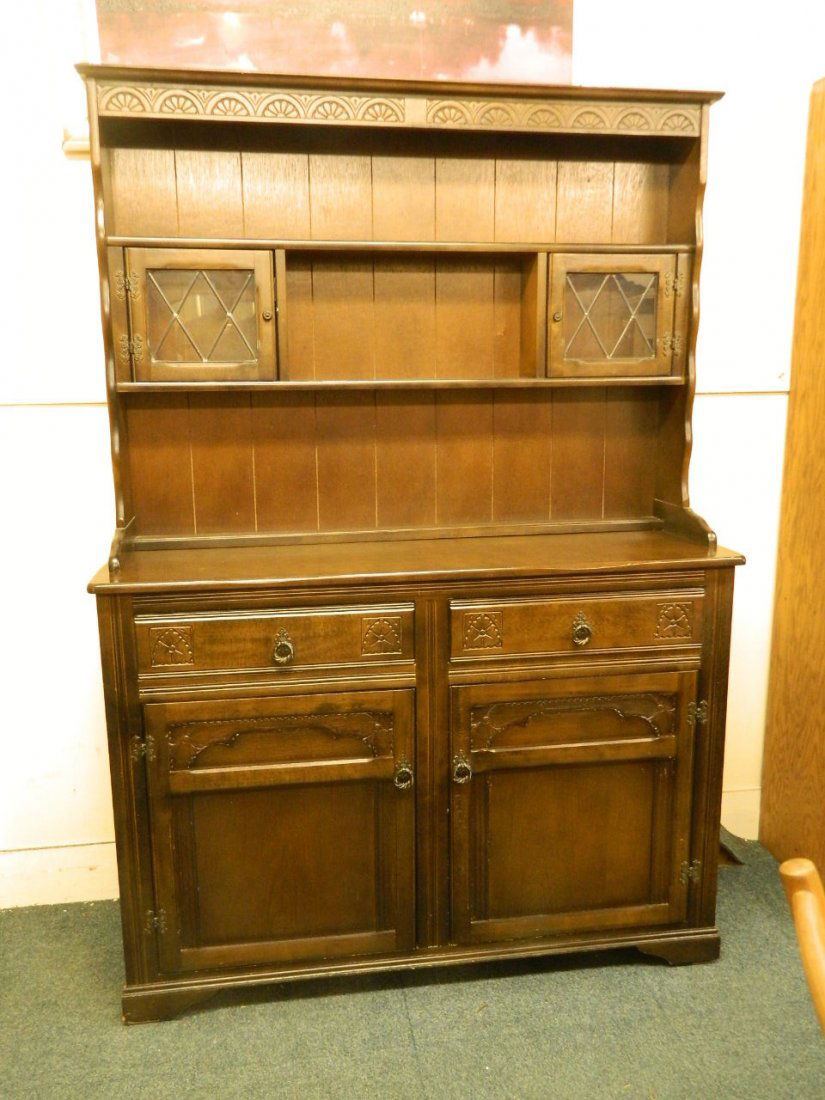 An Ercol dark oak dresser with carved frieze and two: An Ercol dark oak dresser with carved frieze and two glazed doors, 49'' x 19'', 70½'' high
