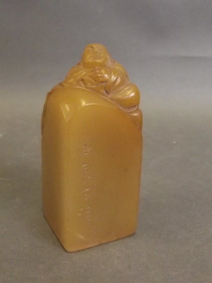 A Chinese yellow soapstone seal with carved decoration: A Chinese yellow soapstone seal with carved decoration of Buddha and inscriptions, 3¾'' high