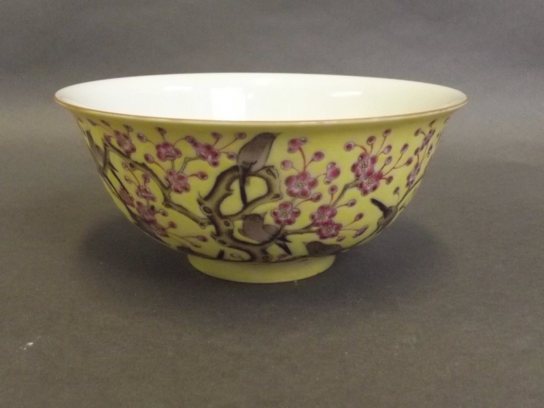 A Chinese yellow ground bowl with enamelled decoration: A Chinese yellow ground bowl with enamelled decoration of birds in a prunus blossom tree, stamp mark to base, 6" diameter
