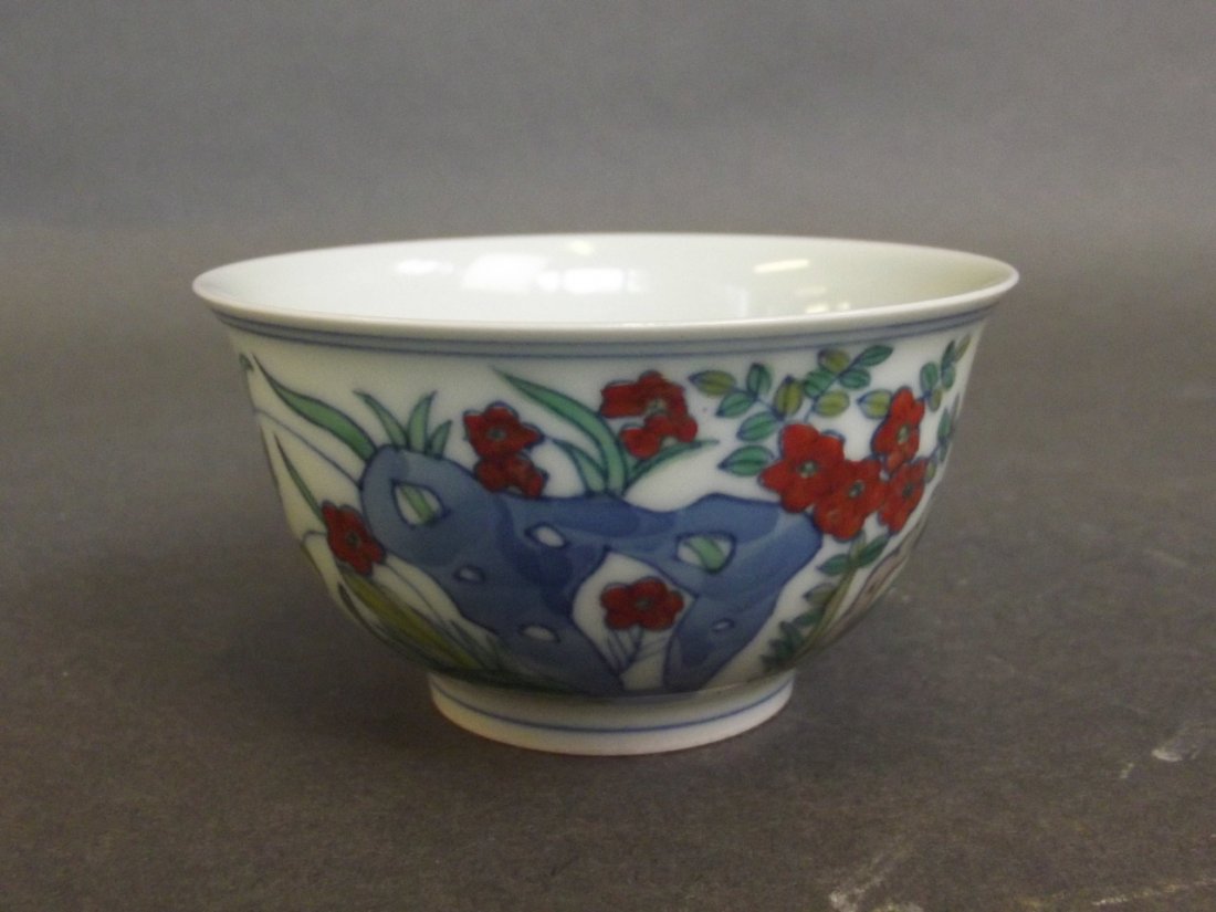 A small Doucai teabowl decorated with flowering trees: A small Doucai teabowl decorated with flowering trees and butterflies, mark to base, 3'' diameter