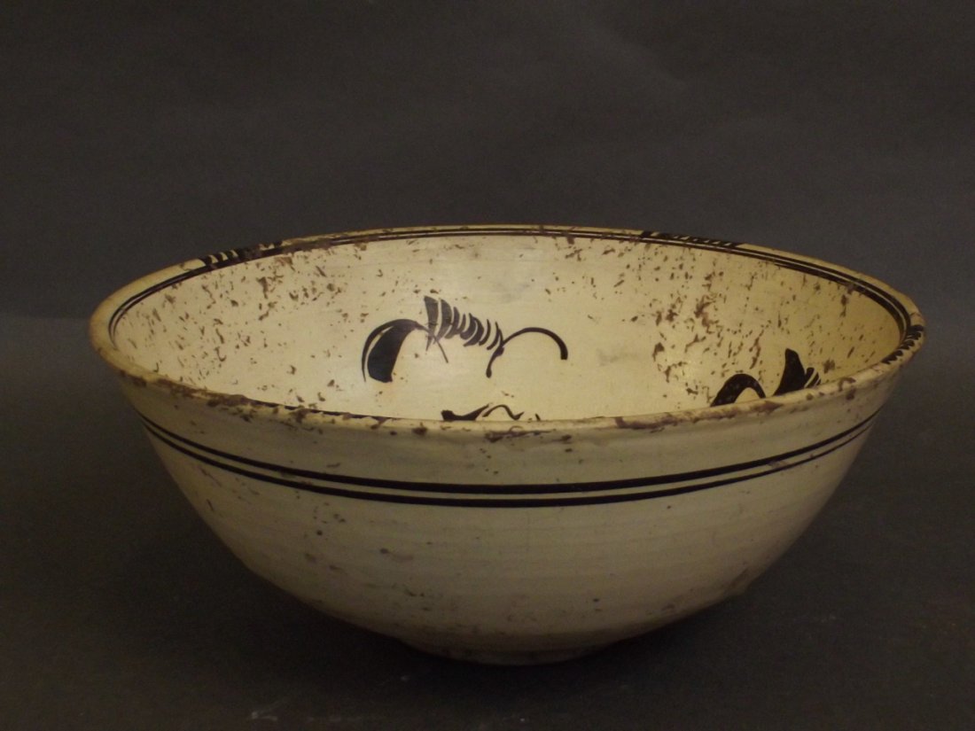 A Chinese Chizhou pottery bowl with dark brown: A Chinese Chizhou pottery bowl with dark brown decoration on a cream ground, 8'' diameter