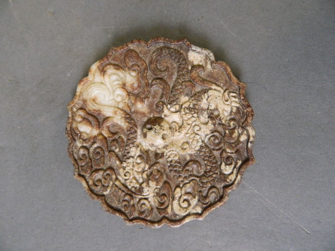 A Chinese brown marbled hardstone pendant with twin: A Chinese brown marbled hardstone pendant with twin carved twin dragon decoration and a petal shaped rim, 3'' diameter